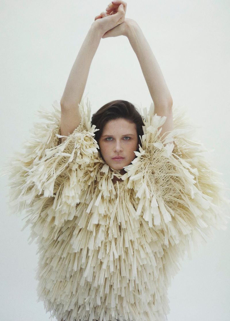 Model Lonneke Te Kloese wearing a textured cream fringed top with arms raised against a seamless white background.
