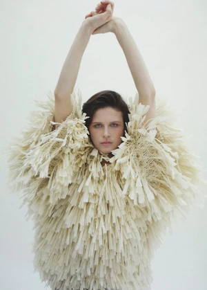Model Lonneke Te Kloese wearing a textured cream fringed top with arms raised against a seamless white background.