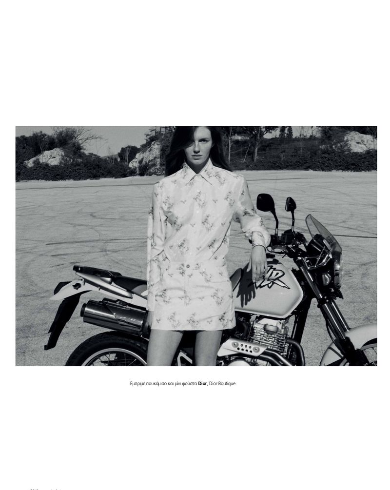 Model leaning against a motorcycle on an asphalt lot for a Marie Claire Greece fashion editorial