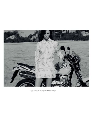 Model leaning against a motorcycle on an asphalt lot for a Marie Claire Greece fashion editorial