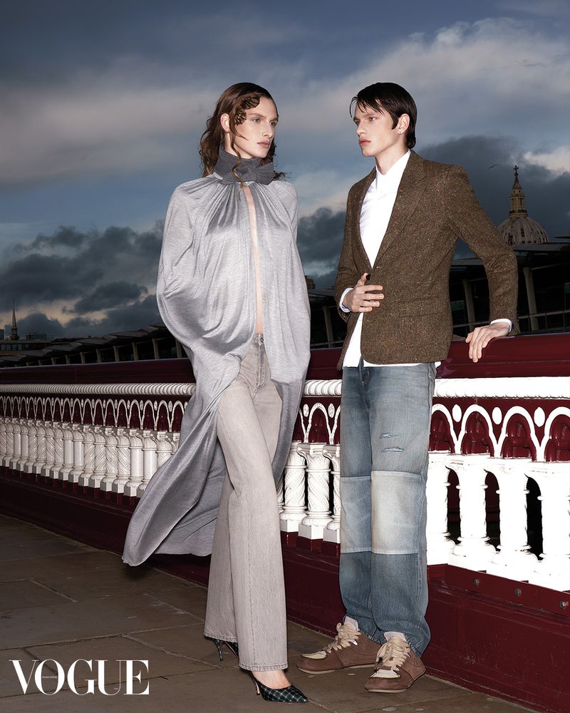 Two models posing outdoors on a bridge against a dramatic cloudy sky for Vogue Hong Kong editorial