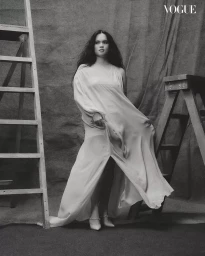 Woman in flowing white gown posing between two wooden ladders for Vogue Philippines Make A Scene editorial