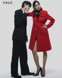 A man in a black suit and a woman in a bright red coat posing against a plain light background for Vogue Philippines.