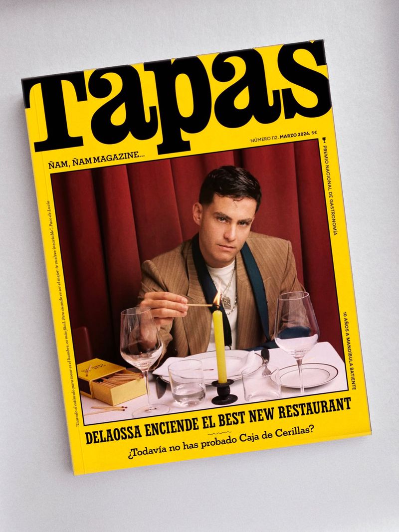 Magazine cover featuring a man in a beige suit jacket lighting a candle at a table set with wine glasses