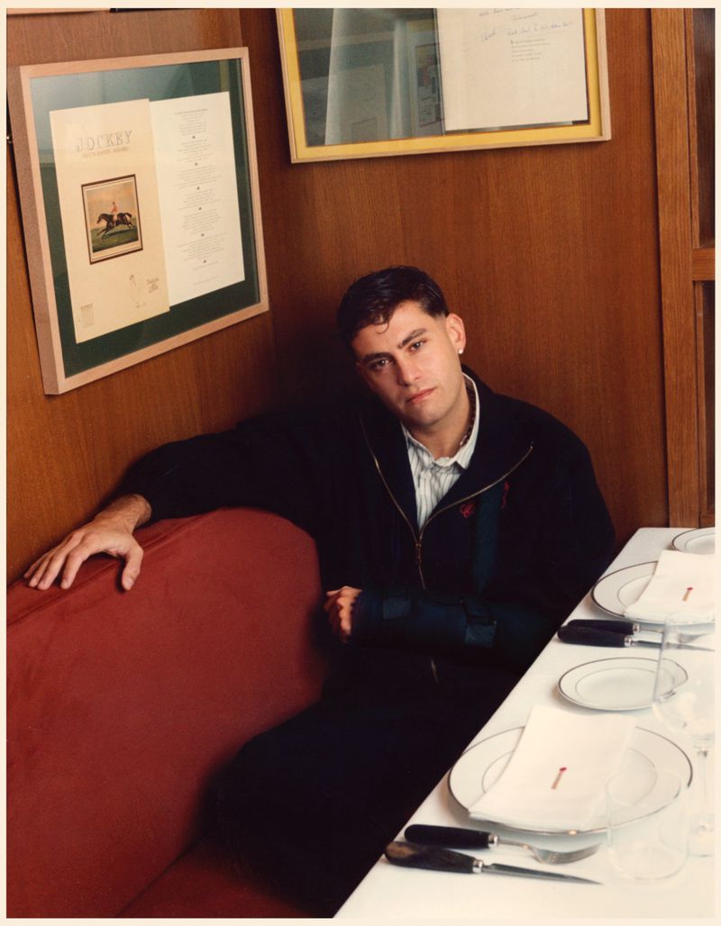 Man seated on a red booth in a wood-paneled restaurant for Tapas Magazine by photographer Fede Delibes