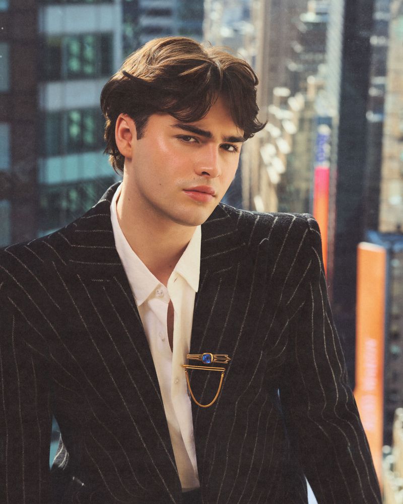 Portrait of a young man wearing a pinstripe jacket over a white shirt against an out-of-focus city background