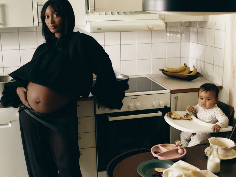 Pregnant woman standing in a domestic kitchen alongside a toddler seated in a high chair, captured by Illya Ovchar for Vogue Scandinavia.