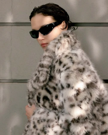 Model in black sunglasses wearing a fluffy animal-print coat against a grey wall for Harper's Bazaar Vietnam.