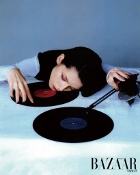 Woman resting her head on vinyl records while touching a turntable in a Harper's Bazaar Taiwan editorial fashion image