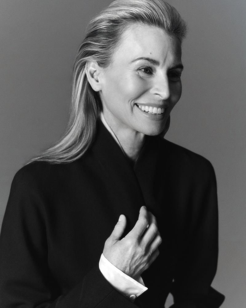 Portrait of model Niki Taylor smiling in a dark jacket against a plain grey backdrop for Harper's Bazaar Australia.