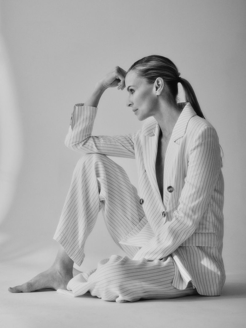 Model Niki Taylor in a pinstripe suit sitting against a seamless backdrop for Harper's Bazaar Australia