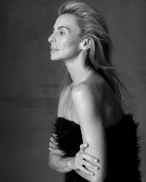 Black and white portrait of model Niki Taylor in profile wearing a textured black top against a dark background