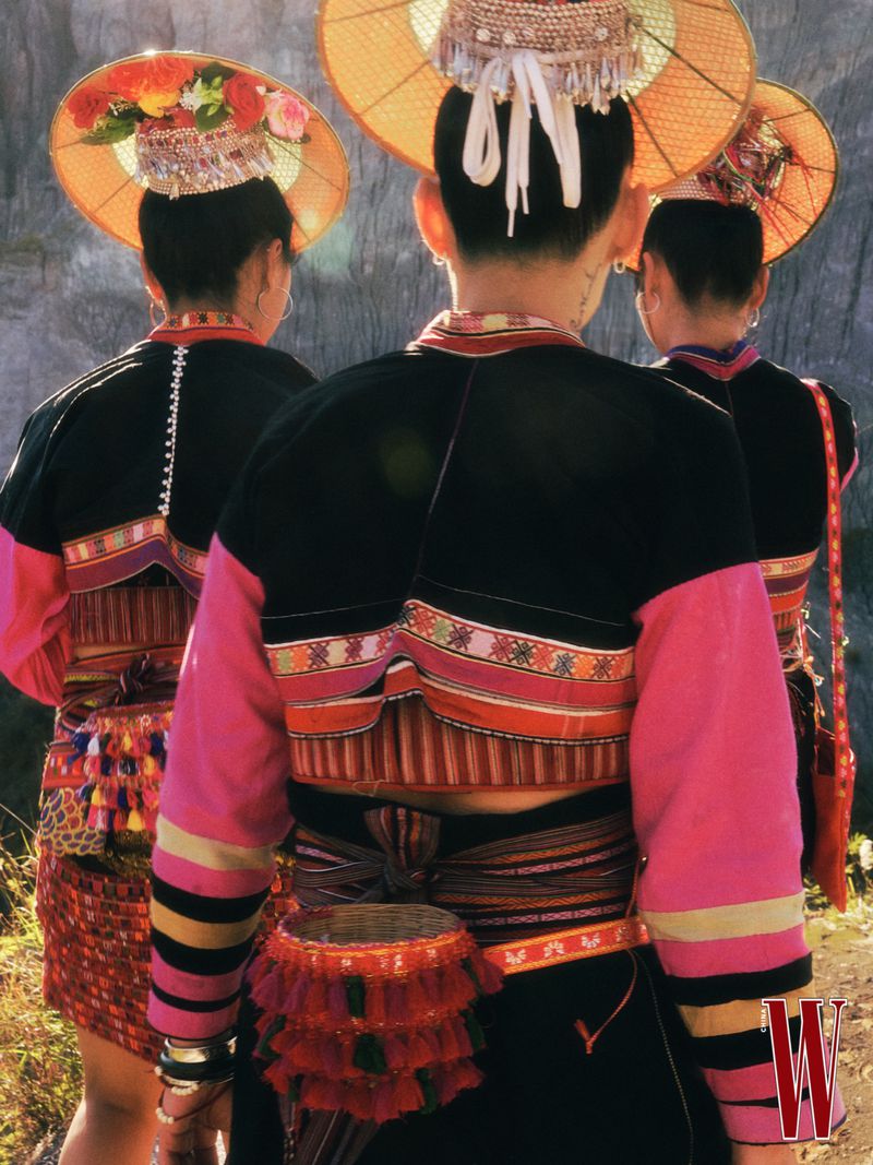 Three models from behind wearing traditional conical hats and patterned black and pink garments for W Magazine China.
