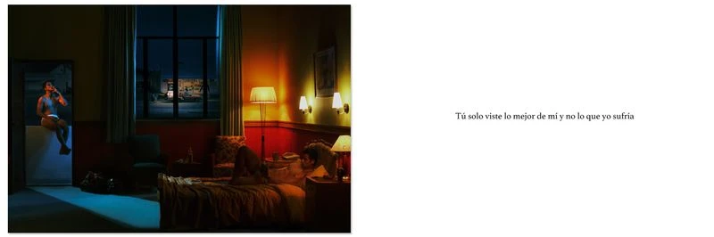 Man lying on a bed in a warmly lit hotel room at night with another person visible in the doorway
