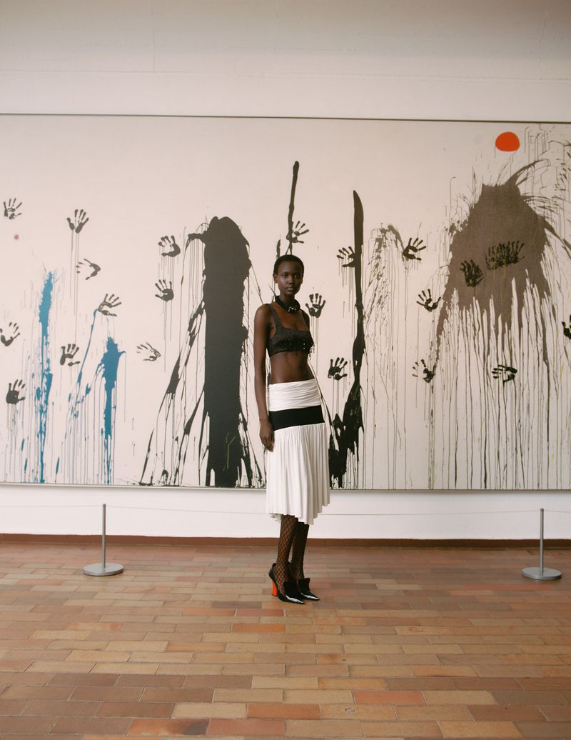 Model standing in front of a large abstract painting with handprint motifs for Vogue Espana photography by Pablo Zamora