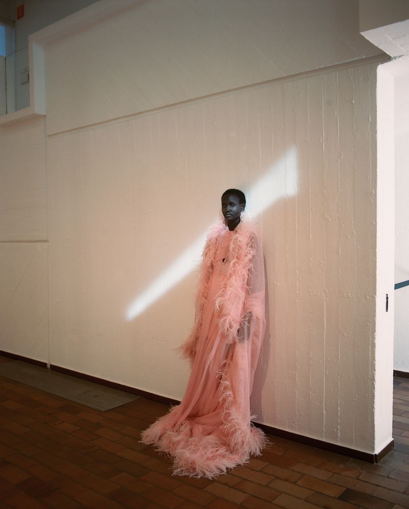 Model Yar Aguer in a pink feathered gown standing against a white wall for Vogue Espana