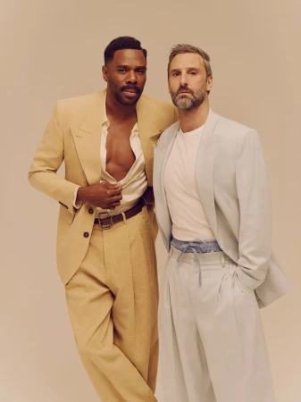 Colman Domingo and Marco Calvani posing together in tailored suits against a neutral background for Out Magazine editorial