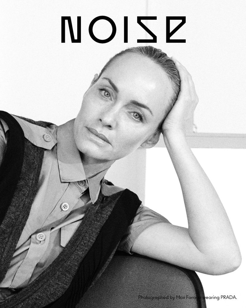 Monochrome portrait of a fair-skinned adult woman with short hair in a button-down shirt and vest, posing in front of a window.