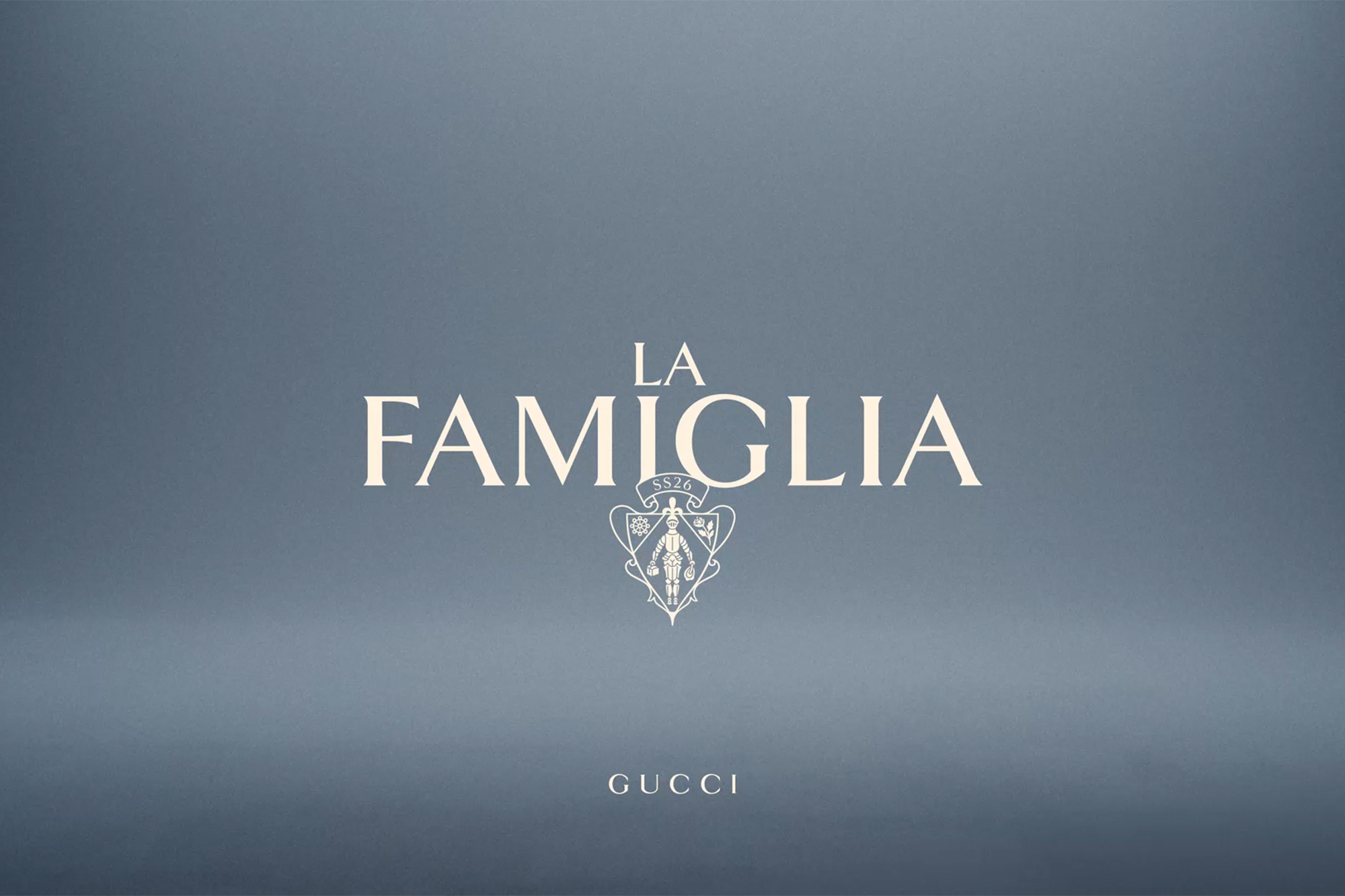 Gucci ad featuring the words 'La Famiglia' in cream text on a gray background with the Gucci logo and brand name.