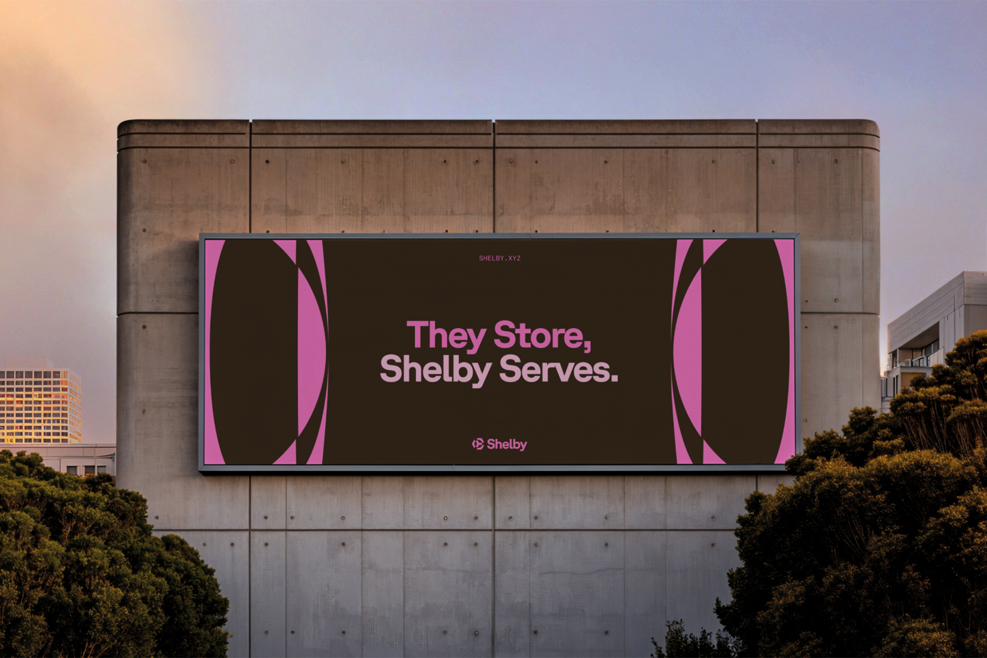 Large outdoor advertising billboard on a concrete building exterior displaying branding with pink typography against a dark brown background.