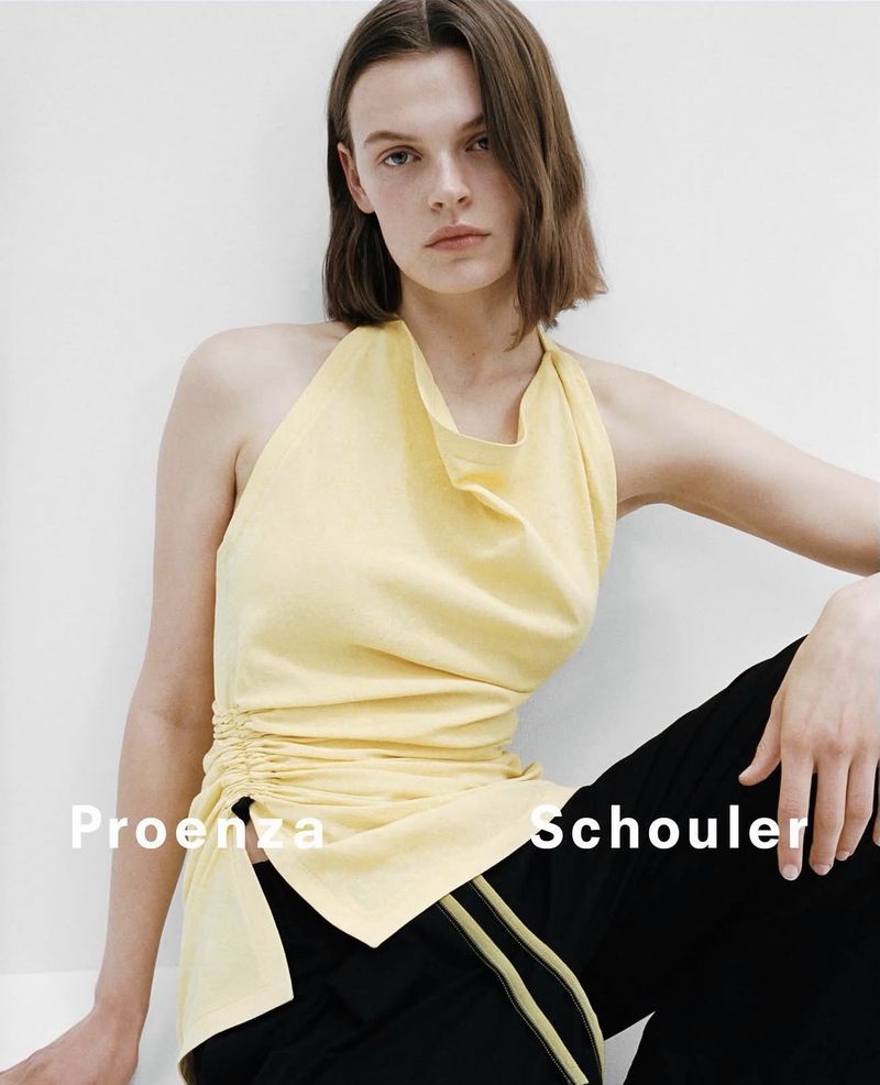 Model wearing a pale yellow halter top and black trousers against a plain white background in Proenza Schouler campaign