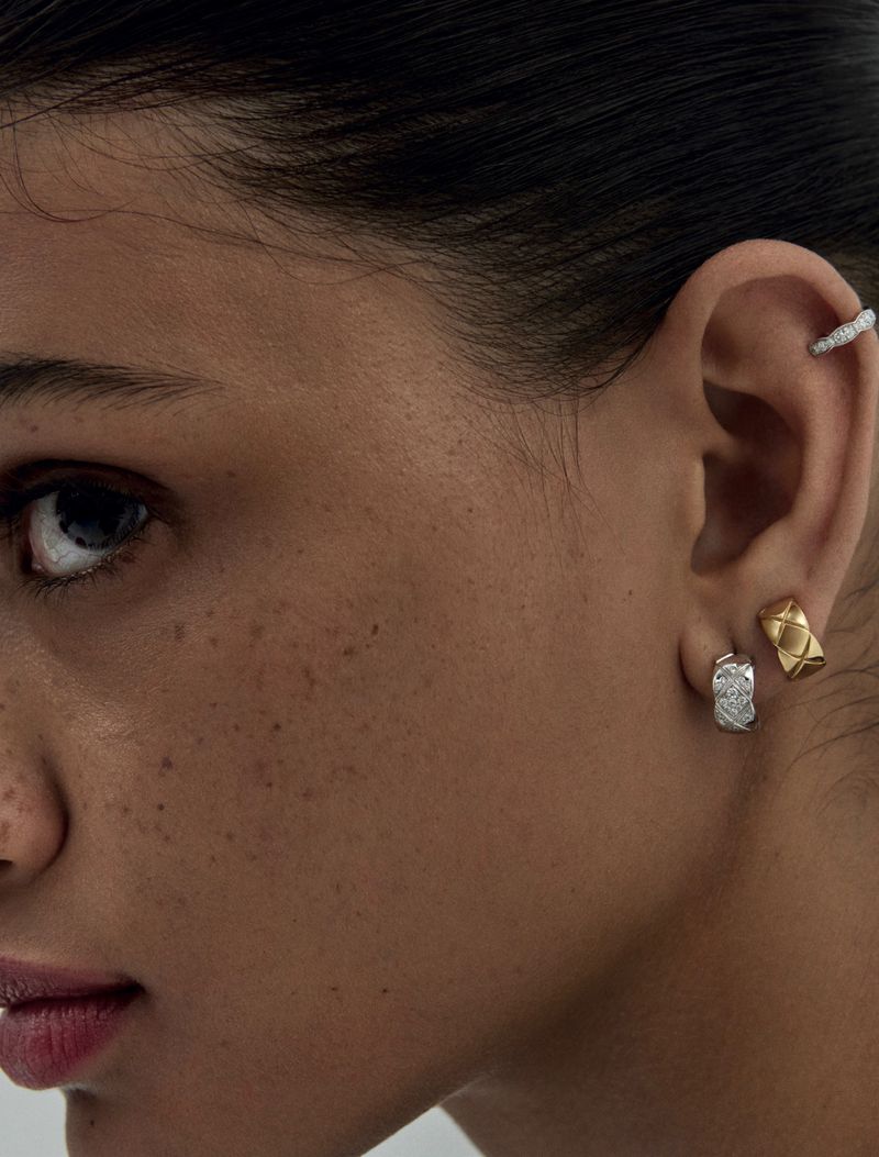 Close-up portrait of a woman showcasing silver and gold hoop earrings and a ear cuff. Focus on beauty and fashion jewelry details.