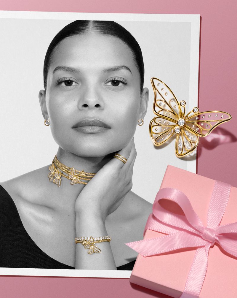 Model wearing gold jewellery including layered necklaces and bracelets alongside a pink gift box