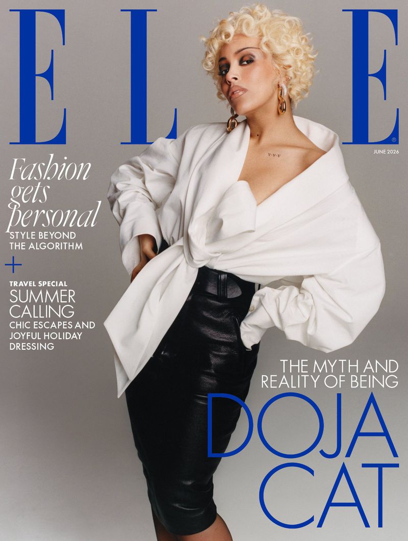 Doja Cat wearing a white draped top and black leather skirt against a grey background for Elle UK magazine cover