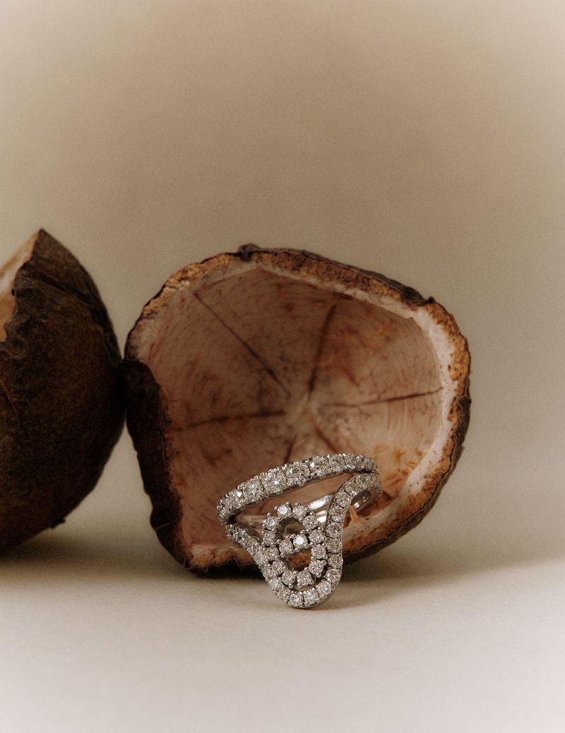Diamond ring resting inside a split hollow seed pod on a neutral beige background