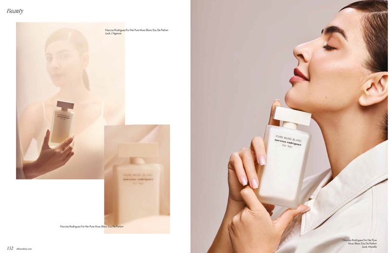 Woman in cream clothing holding a white perfume bottle near her chin in a beauty editorial spread