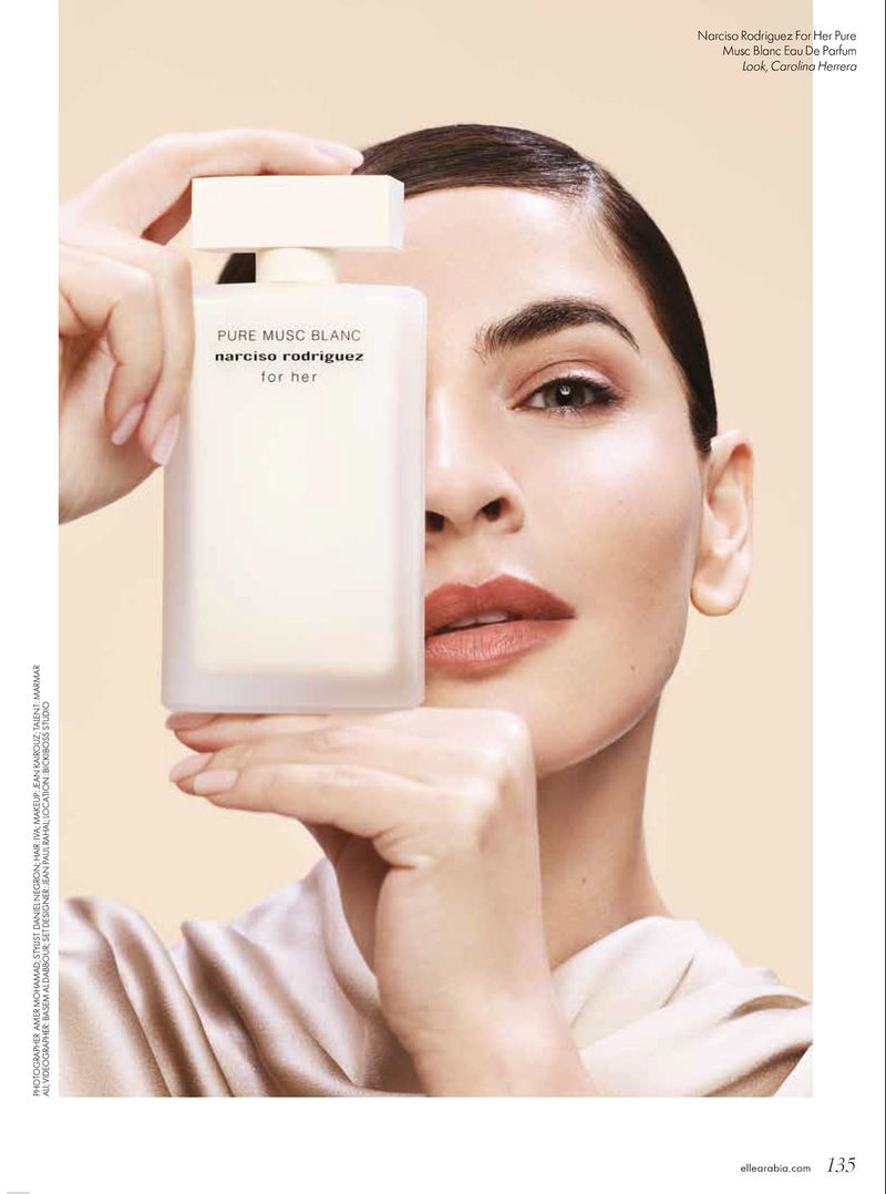 Close-up portrait of a woman holding a white perfume bottle in front of her face for Elle Arabia.