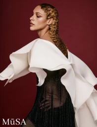 Model in sculpted white ruffled top and black dress against a dark red background with finger-waved hair