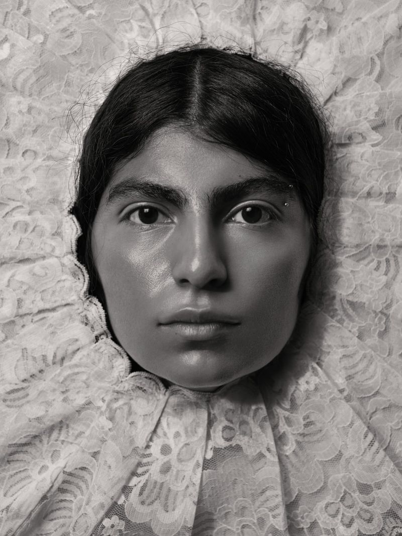 Close-up portrait of a woman framed by intricate white lace ruff collar in monochrome photography