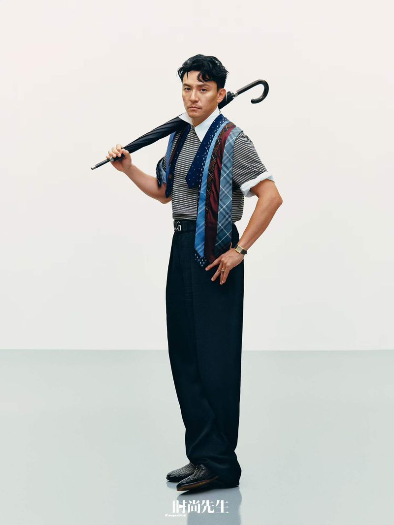 Man holding an umbrella over his shoulder wearing striped polo, dark trousers, and multiple ties for Esquire China cover