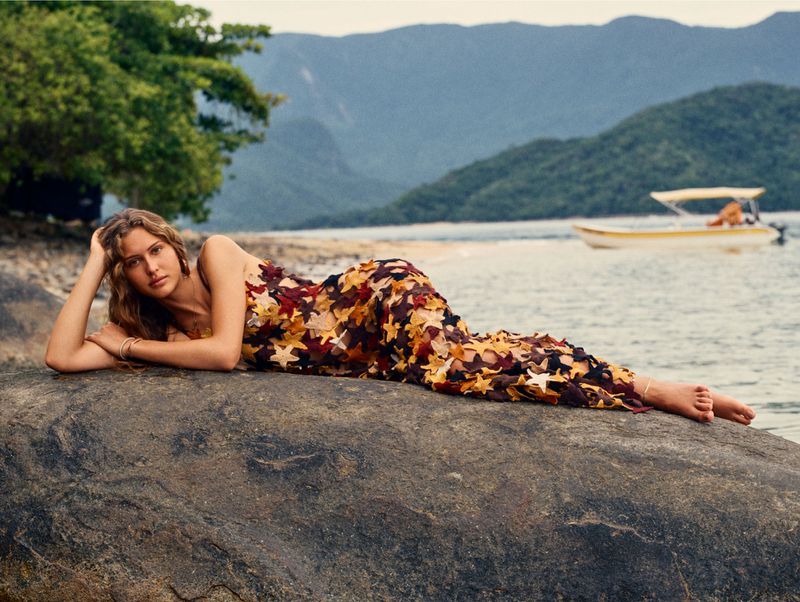Model Angelina Kendall lying on a coastal rock wearing a leaf-patterned dress for Financial Times HTSI Magazine.