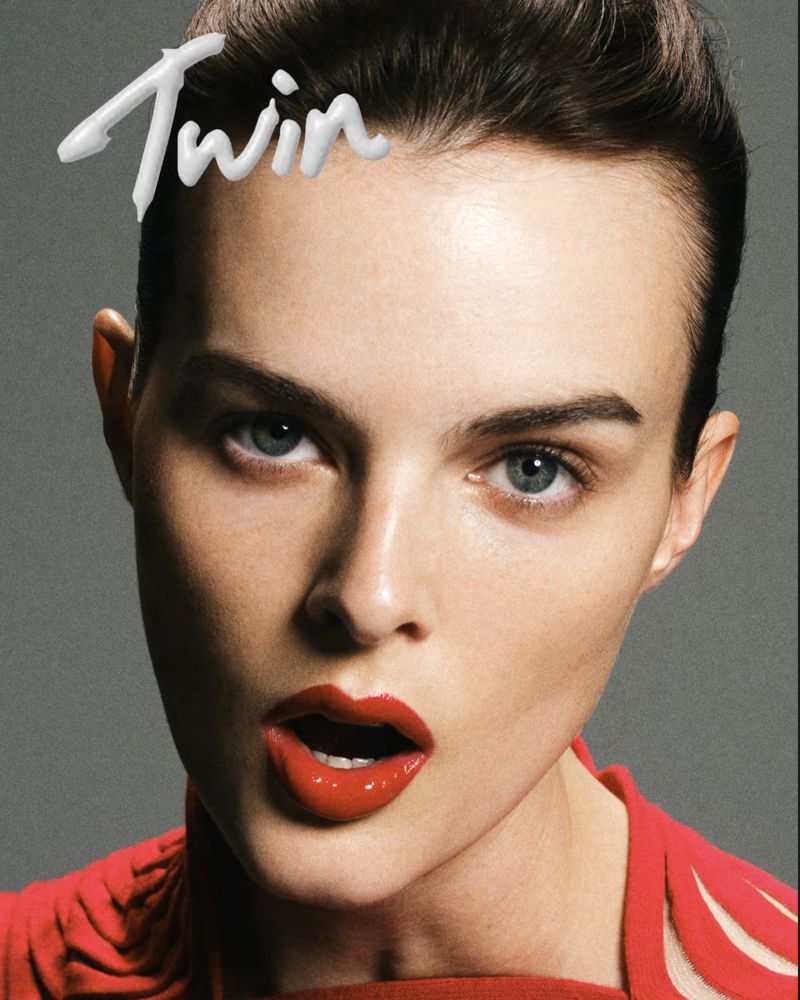 Close-up fashion portrait of a fair-skinned adult woman with red lips, a red top, and the word 'Twin' above her head.