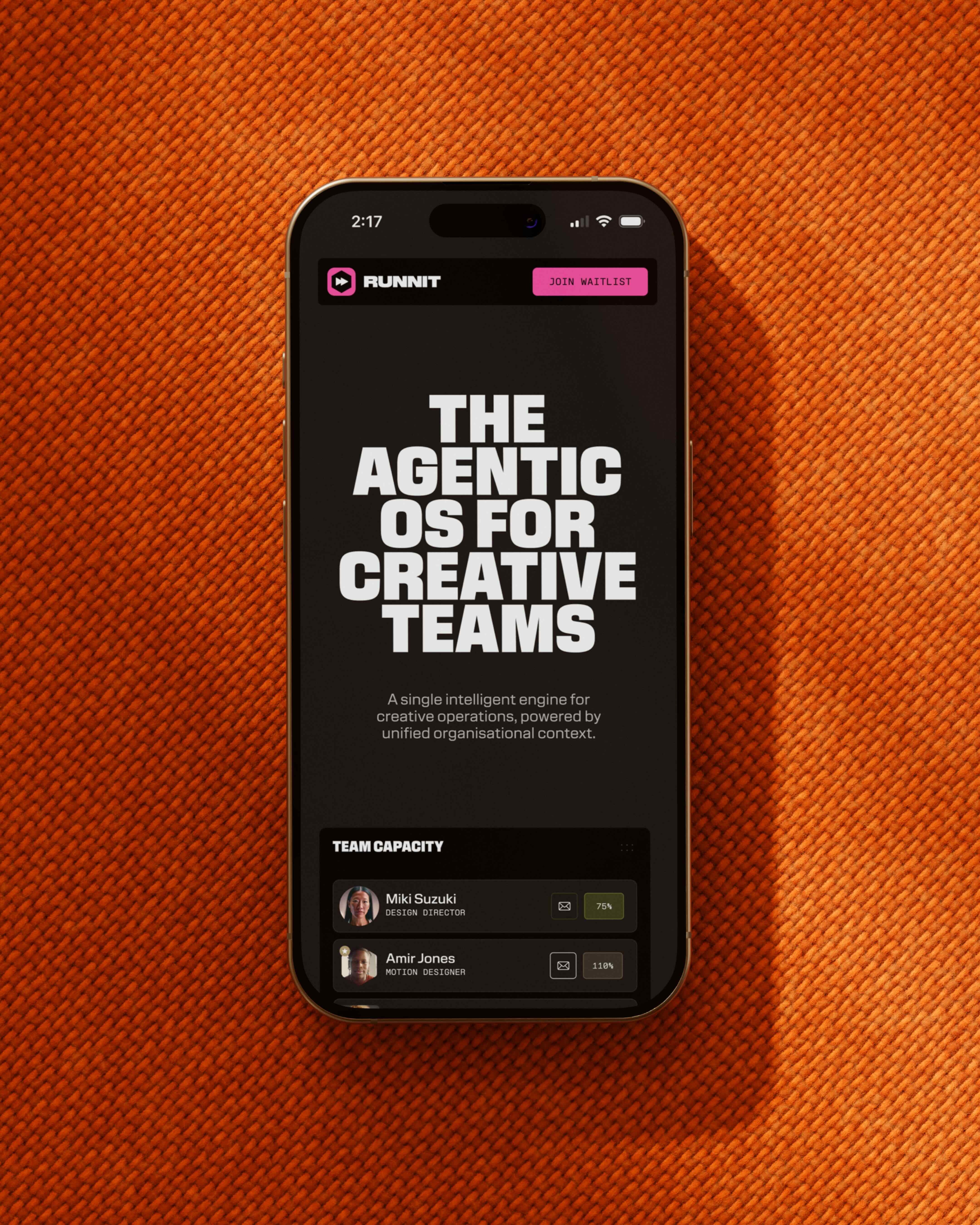 Smartphone displaying a dark-mode app interface resting flat on a textured orange fabric surface.