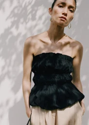 Charlotte Carey wearing a black strapless smocked peplum top and beige trousers in Mango Urban Summer SS25 campaign.