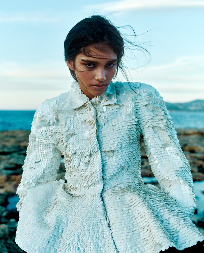Model wearing a textured white sequin jacket outdoors near the ocean for a Vogue Netherlands fashion editorial by Zoe Karssen.
