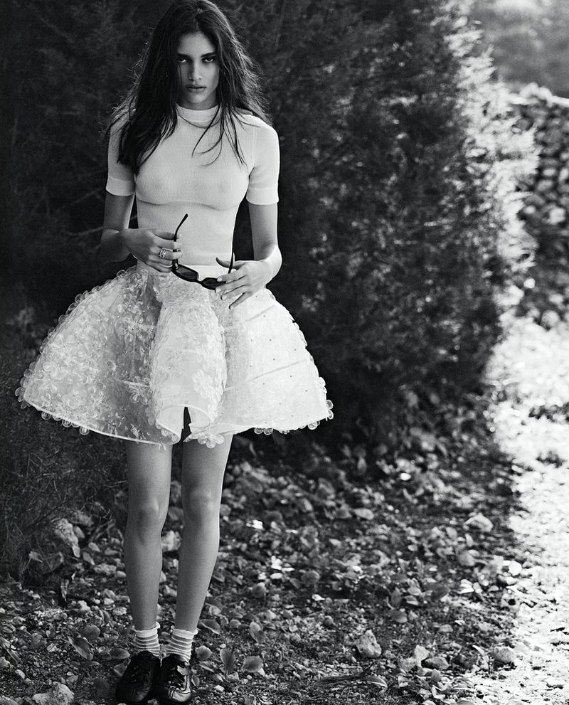 Model Elina Gunawardena posing outdoors wearing a white short-sleeve top and flared skirt for Vogue Netherlands