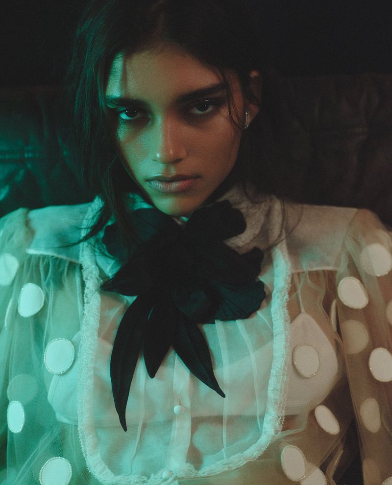 Model Elina Gunawardena wearing a sheer white polka dot blouse with a large black bow for Vogue Netherlands by Zoe Karssen