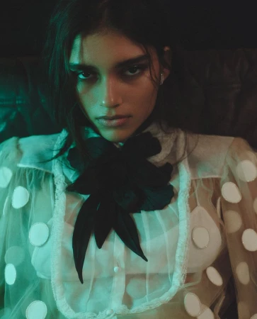 Model Elina Gunawardena wearing a sheer white polka dot blouse with a large black bow for Vogue Netherlands by Zoe Karssen