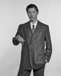 Model Daisuke Ueda wearing a grey tailored suit and tie for Corneliani, photographed by Simone Battistoni in monochrome.