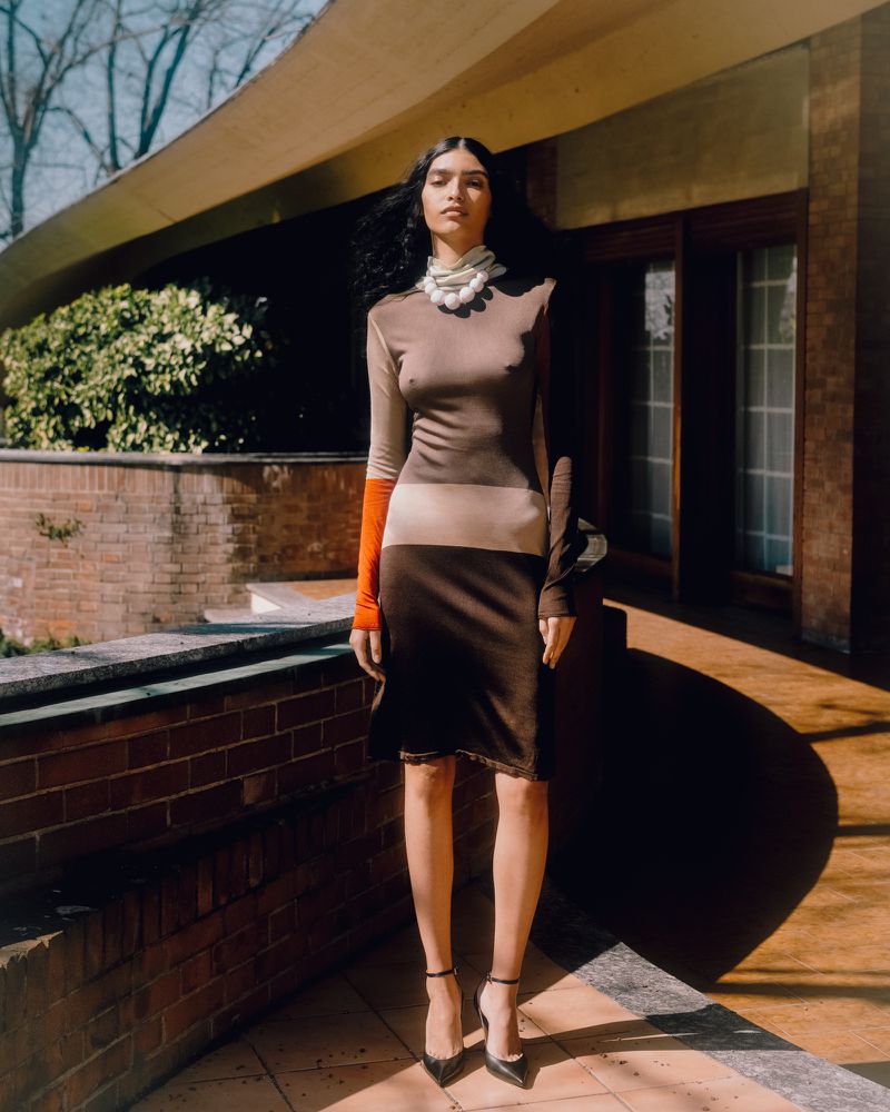 Model standing outdoors on a tiled terrace wearing a colour-blocked dress and chunky necklace for Z Magazine.