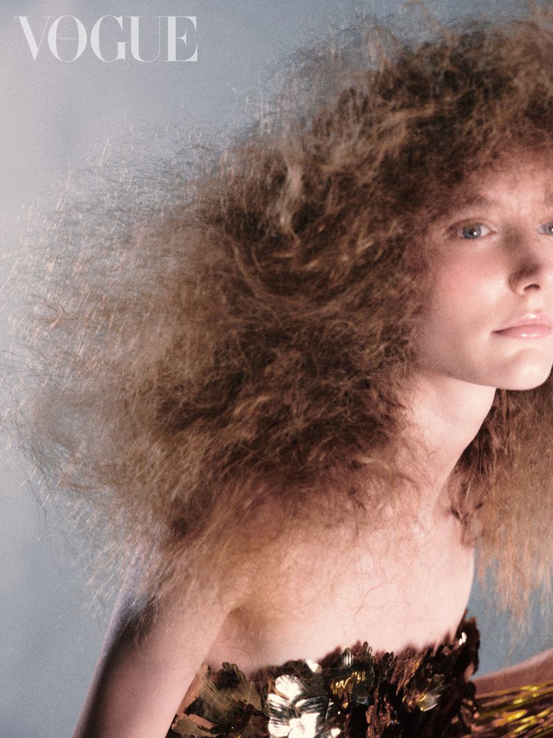 Close-up portrait of a woman with voluminous textured hair wearing a metallic sequined garment for Vogue Portugal