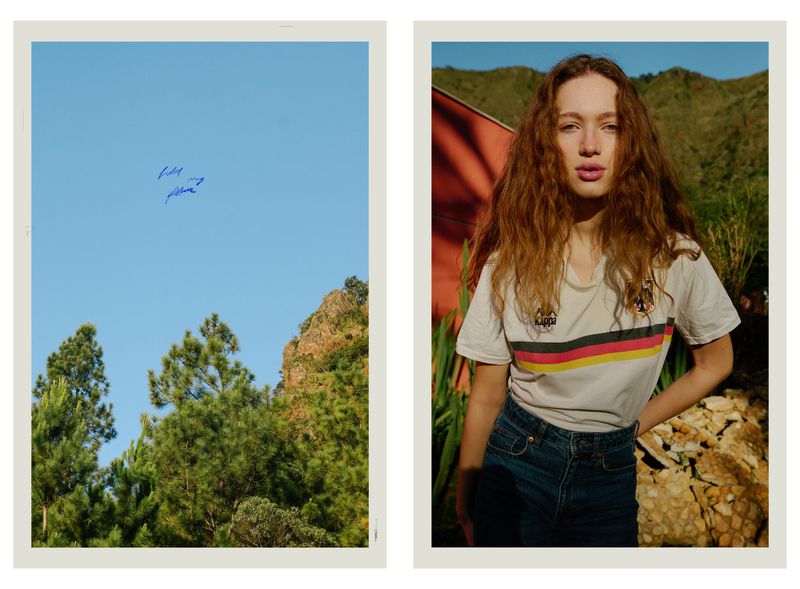 Woman with long curly brown hair wearing a white t-shirt and blue jeans outdoors with hills in the background, paired with a sky landscape panel.