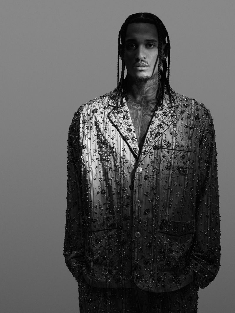 Monochrome portrait of Jordan Clarkson wearing an embellished textured jacket against a plain grey backdrop.
