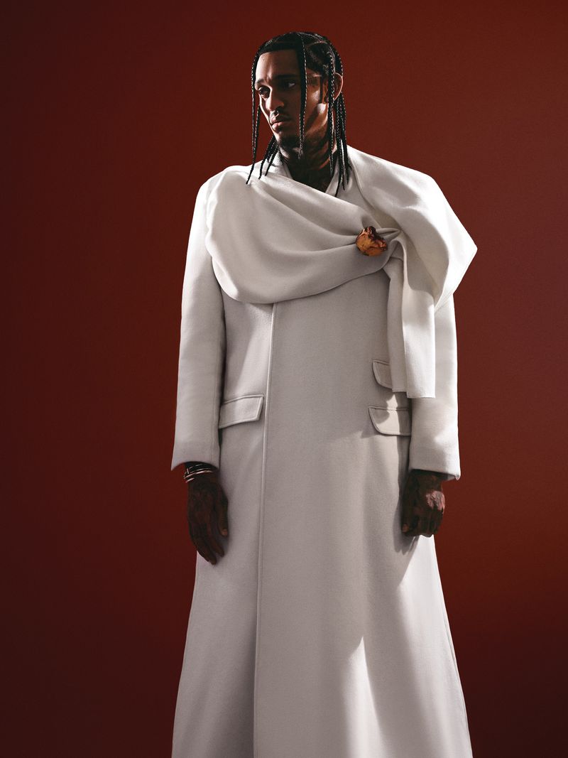 Jordan Clarkson wearing an off-white sculptural coat against a dark red background for a Flaunt magazine editorial portrait