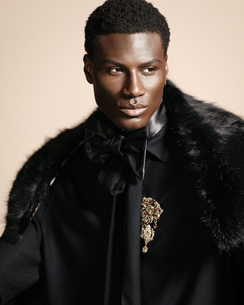 Portrait of a black male model in a black shirt and faux fur stole for Flanelle Magazine