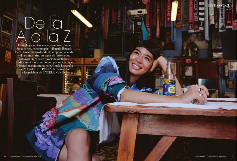 Woman in patterned blue top leaning on a wooden table inside a restaurant with sports memorabilia on walls